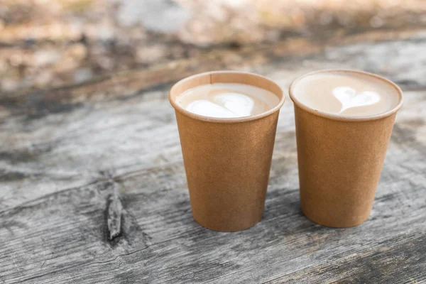 Dua cangkir kopi kertas dengan bentuk hati seni latte di latar belakang kuning — Stok Foto