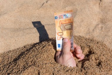 Kumdan çıkmış bir adamın elinde 50 euro var. Finans parası tatili kavramı.
