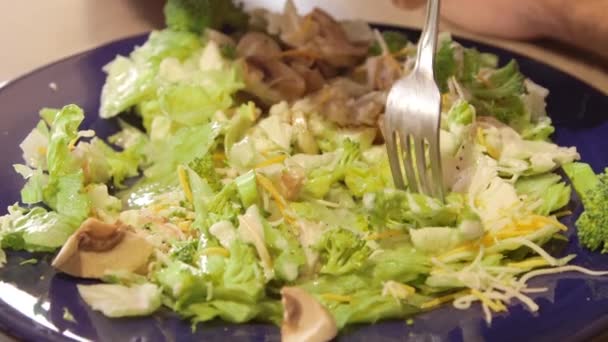 Мужчина ест салат из свежих овощей и салата — стоковое видео