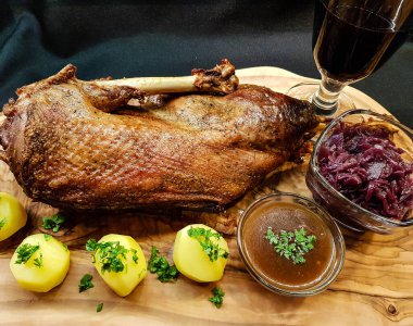 Kızarmış kaz, patates, lahana ve bir kadeh kırmızı şarap.