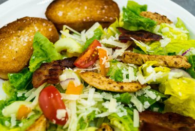 Izgara tavuk pastırmalı geleneksel sezar salatası ve tuzlu sarımsaklı ekmek.