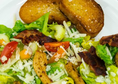 Izgara tavuk pastırmalı geleneksel sezar salatası ve tuzlu sarımsaklı ekmek.