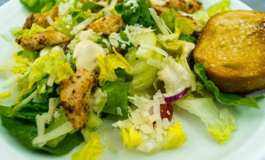 Izgara tavuk pastırmalı geleneksel sezar salatası ve tuzlu sarımsaklı ekmek.