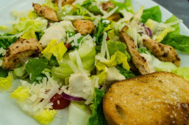 Izgara tavuk pastırmalı geleneksel sezar salatası ve tuzlu sarımsaklı ekmek.