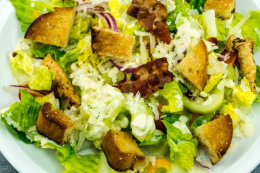 Izgara tavuk pastırmalı geleneksel sezar salatası ve tuzlu sarımsaklı ekmek.