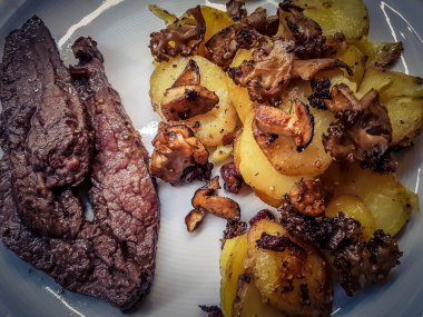 Orman mantarlı biftek ve kızarmış patates.