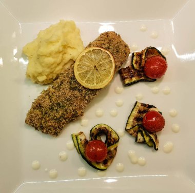 Kızarmış somon bifteği, patates püresi ve kızarmış sebze.