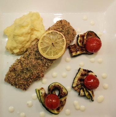 Kızarmış somon bifteği, patates püresi ve kızarmış sebze.