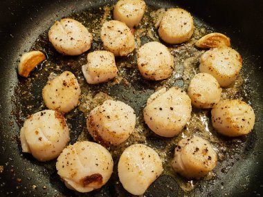 Kızarmış tuzlu deniz kabukları ve yeşil soslu spagetti.