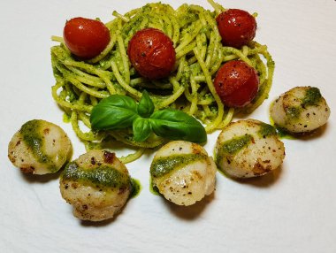 Kızarmış tuzlu deniz kabukları ve yeşil soslu spagetti.
