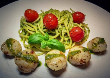 Kızarmış tuzlu deniz kabukları ve yeşil soslu spagetti.