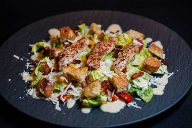 Izgara tavuk pastırmalı geleneksel sezar salatası ve tuzlu sarımsaklı ekmek.