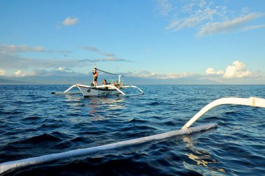 LOVINA, INDONEZYA-AĞUSTOS 28 2016: Yunuslar Lovina sahilinde sabah veya gündüz erken saatlerde yerel halkın geleneksel balıkçı teknesini kullanarak turneye çıktılar.