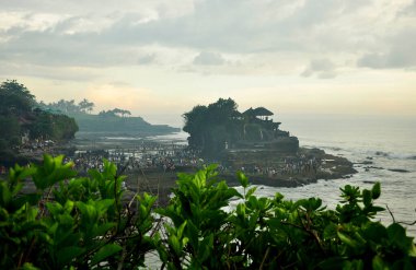 TABANAN, INDONEZYA-AĞUSTOS 30 2016: Siyah kum ve kayalarla çevrili Bali Endonezya 'nın Tabanan naipliğindeki Tanah Lot' un güzel tapınağı.