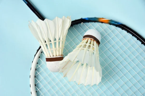 Badminton Shuttelcock ve raketi arka plan olarak açık mavi renkte izole edilmiş.
