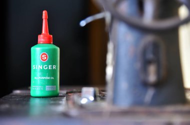BALI, INDONEZYA-JULY 22 Temmuz 2021: Singer 'ın dikiş makinesi yağı eski Kelebek Dikiş Makinesinin yanında