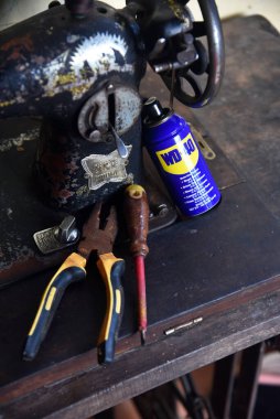 BALI, İNDONEZYA-HAZİRAN 22 HAZİRAN 2021: WD 40 yağı, eski dikiş makinesine yerleştirilmiş bir tong ve tornavida ile