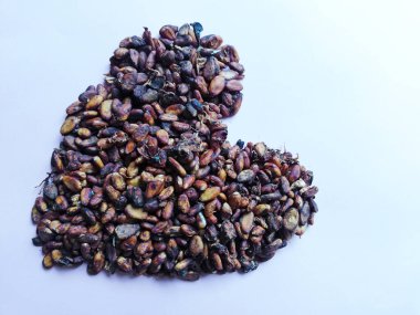 Cacao beans in heart or love form isolated on color background