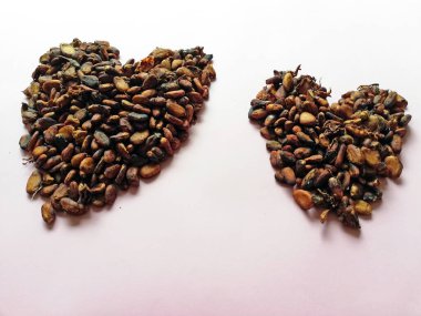 Cacao beans in heart or love form isolated on color background