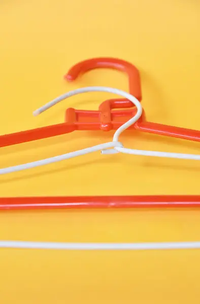Cloth hanger in red and white color on yellow background