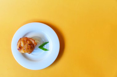 Arka planda küçük beyaz tabakta servis edilen kızarmış muz.