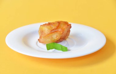 Arka planda küçük beyaz tabakta servis edilen kızarmış muz.