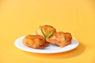 Arka planda küçük beyaz tabakta servis edilen kızarmış muz.