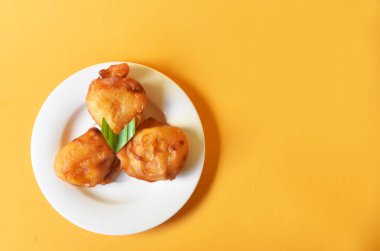 Arka planda küçük beyaz tabakta servis edilen kızarmış muz.