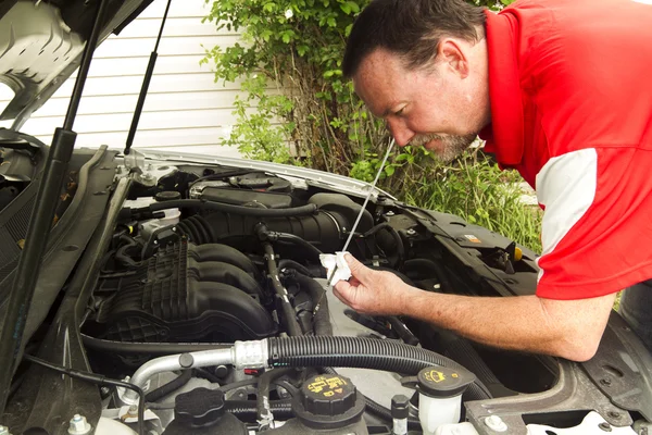 Um mecânico verificando o óleo em um carro mais novo — Fotografia de Stock