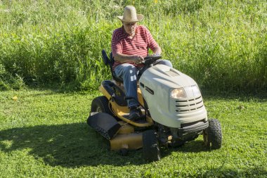 Büyük erkek bir hasır şapka çim biçme makinesi sürme