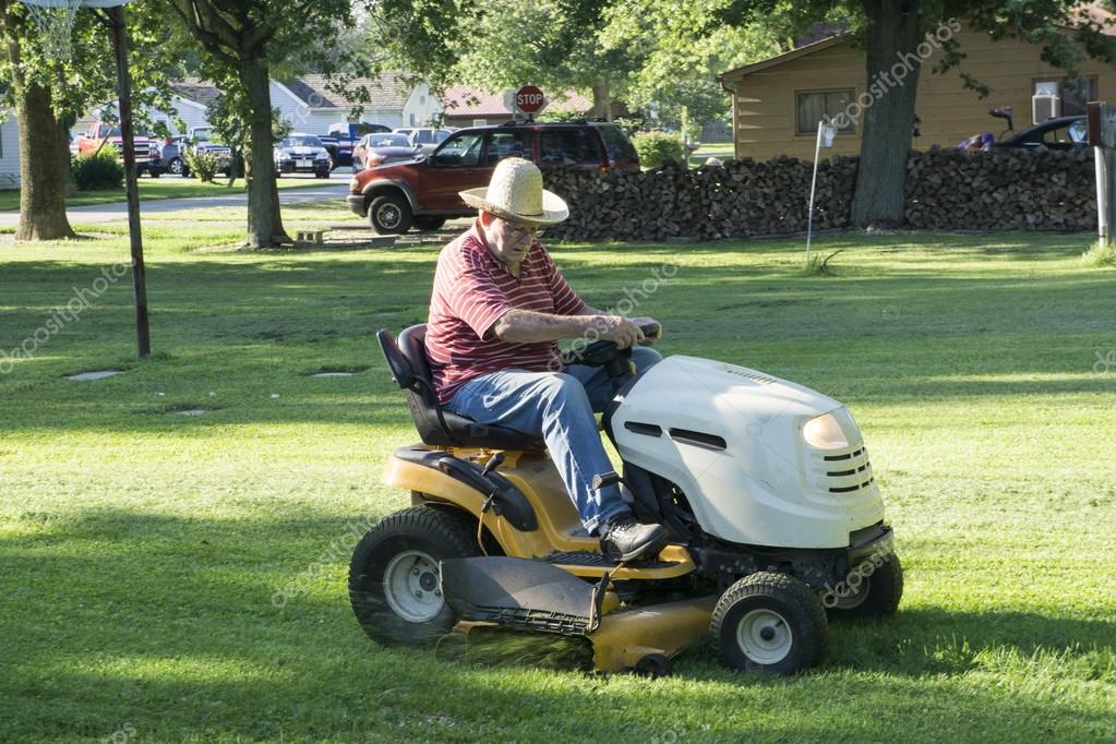 Senior Citizen Cutting Grass With A Straw Hat On Stock Photo by