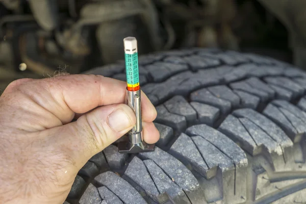 Usando um medidor de desgaste de piso em um pneu de caminhão — Fotografia de Stock