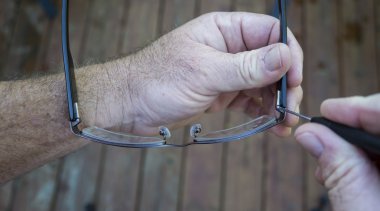 Using A Precision Screwdriver To Tighten Screw On Glasses clipart