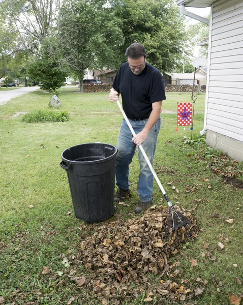 Propriétaire ratissage des feuilles dans la cour avant — Photo