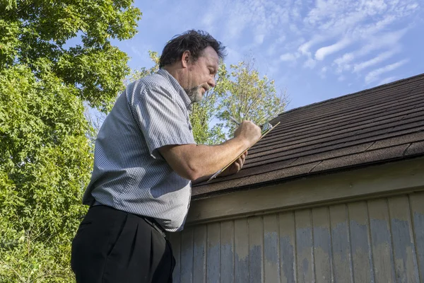 Ajustador de seguros que calcula el daño del granizo al techo — Foto de Stock