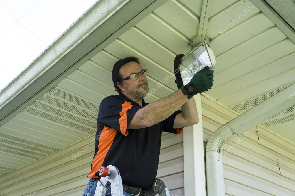 Electrician Changing A Bulb In Outside Light Fixture