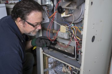 Technician Looking Over A Gas Furnace clipart