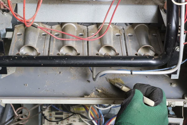 Tecnico utilizzando spazzola per pulire sotto i bruciatori — Foto Stock