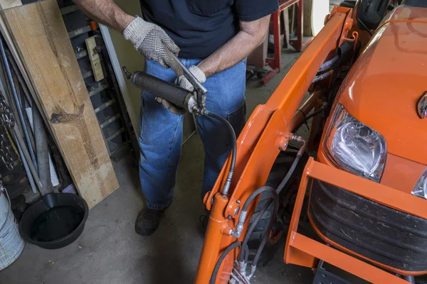 Mécanicien utilisant un pistolet à graisse sur un tracteur — Photo