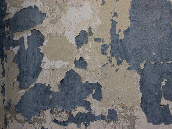 Rengi solmuş eski bir beton duvar. Yüzey boyalı, pürüzlü, yıpranmış, desenli, çatlaklı ve soyulmuş..