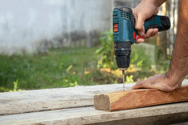 Marangoz tahtayı delmek için elektrikli matkap kullanıyordu..