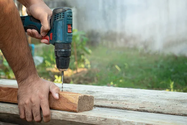 The carpenter was using an electric drill to drill into the wood.