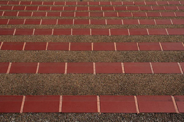 Kırmızı fayansla kaplı kaldırım taşından bir merdiven, üst köşeden alınmış..