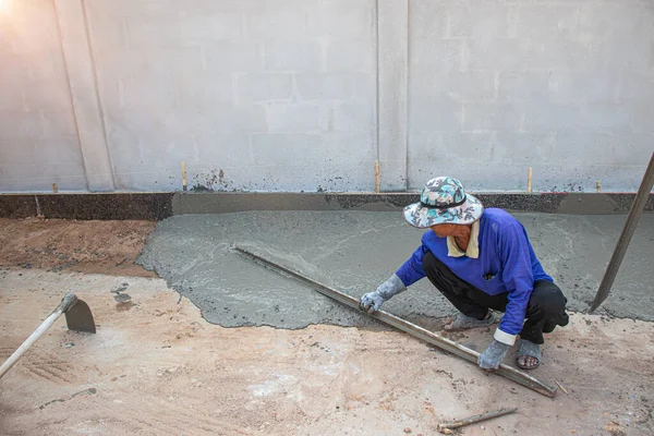 Sıva işi. The tiler çimento yüzeyini düzleştirmeye çalışıyor..