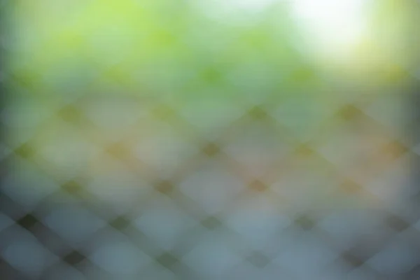 Çelik kafes örgüsüyle soyut bir arkaplan ve bulanık bir doğa..