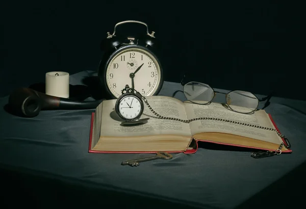 Natürmort bir kitap ve koyu renklerde saatler