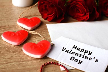 Kırmızı gül, beyaz zarf ve kurdeleler. Sevdiklerine bir hediye.