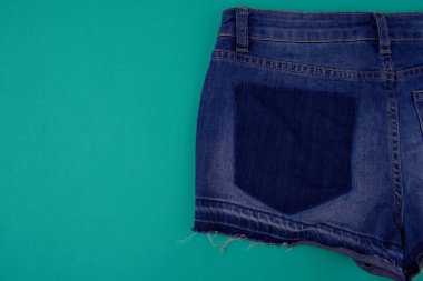 Mavi kot şortun yarısı kapalı, mavi arkaplanda arka plan boş alanın yanında. Kotun cebi yetersiz.