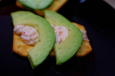 Krakerin üzerinde dilimlenmiş avokado ve yakın plan peynir. Sağlıklı bir atıştırmalık Biraz alan derinliği.