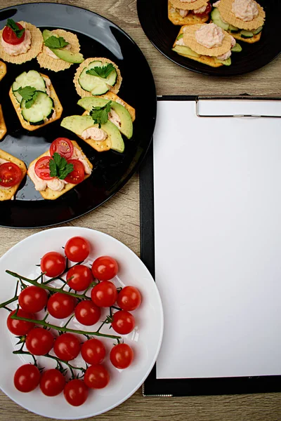 记事本上有一张白纸做笔记 围绕着饼干和碎蔬菜的小吃 待办事项清单 复制空间 — 图库照片